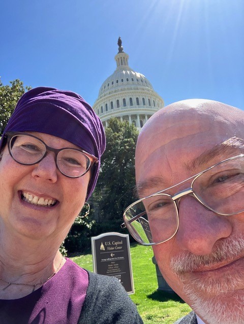 Close-up photo of Bessie Weiss and Sam Abel-Palmer with Capitol dome behind them