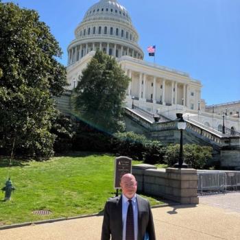 Sam wearing a suit standing in front of US Capitol